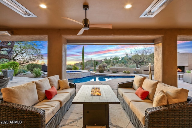 patio terrace at dusk featuring ceiling fan, a swimming pool with hot tub, and an outdoor hangout area