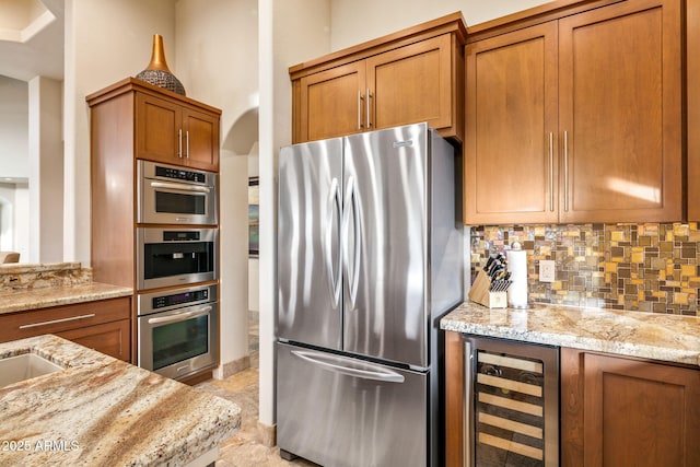 kitchen featuring decorative backsplash, stainless steel fridge, wine cooler, and light stone countertops