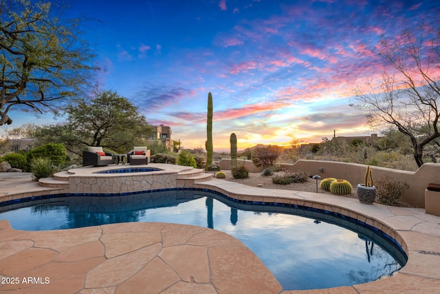 pool at dusk with an in ground hot tub and a patio area