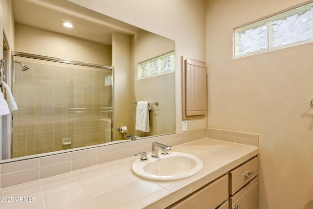 bathroom with plenty of natural light, a shower with shower door, and vanity