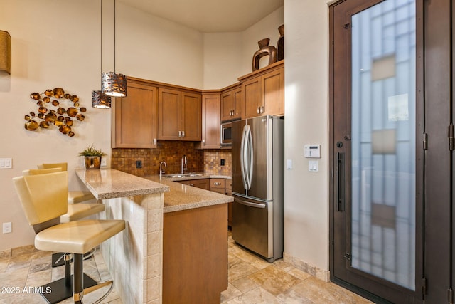 kitchen featuring kitchen peninsula, appliances with stainless steel finishes, backsplash, a breakfast bar, and pendant lighting