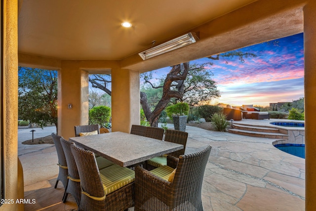 patio terrace at dusk featuring a swimming pool with hot tub