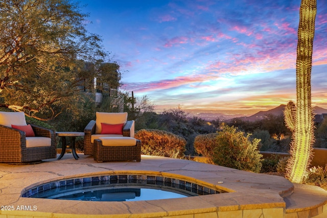 pool at dusk featuring an in ground hot tub and a mountain view