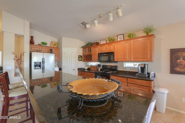 kitchen featuring a spacious island, vaulted ceiling, brown cabinets, black appliances, and a kitchen bar