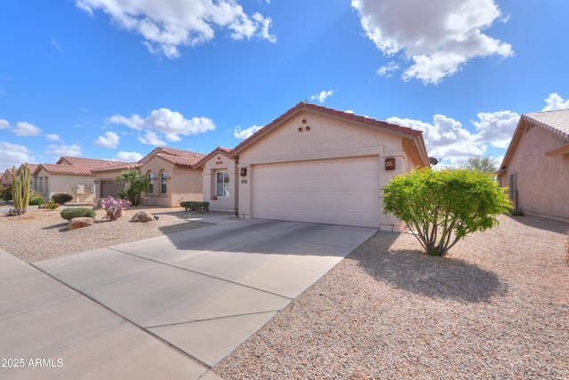 mediterranean / spanish-style home featuring an attached garage, driveway, a tiled roof, and stucco siding