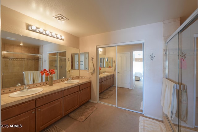 bathroom featuring double vanity, a stall shower, visible vents, and a sink