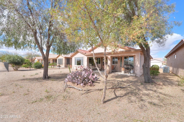 rear view of house with a patio, stucco siding, central AC unit, fence, and a tiled roof