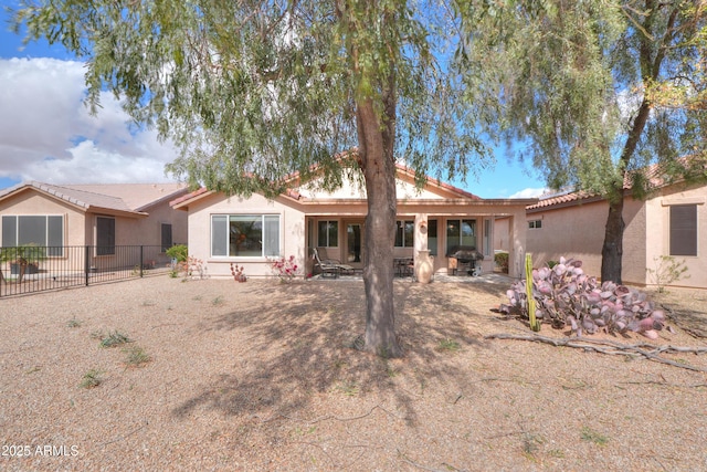 rear view of property featuring a patio, fence, and stucco siding