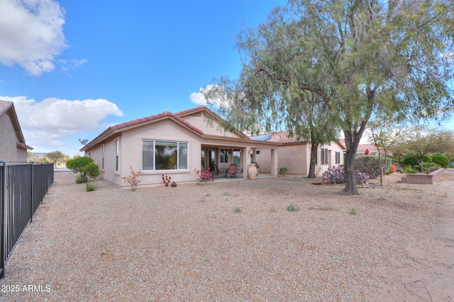 view of front of property featuring a patio area, a tile roof, fence, and stucco siding