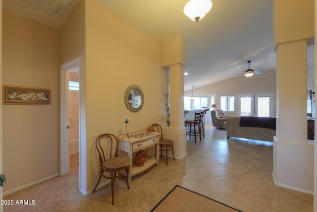 hallway with lofted ceiling, light tile patterned floors, visible vents, baseboards, and decorative columns