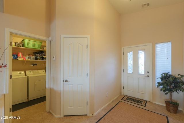 entrance foyer with light tile patterned floors, a high ceiling, visible vents, and separate washer and dryer