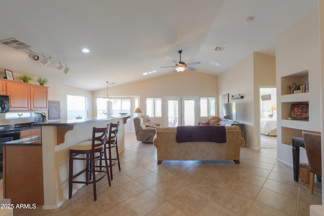 kitchen with visible vents, dark countertops, a breakfast bar, vaulted ceiling, and black microwave