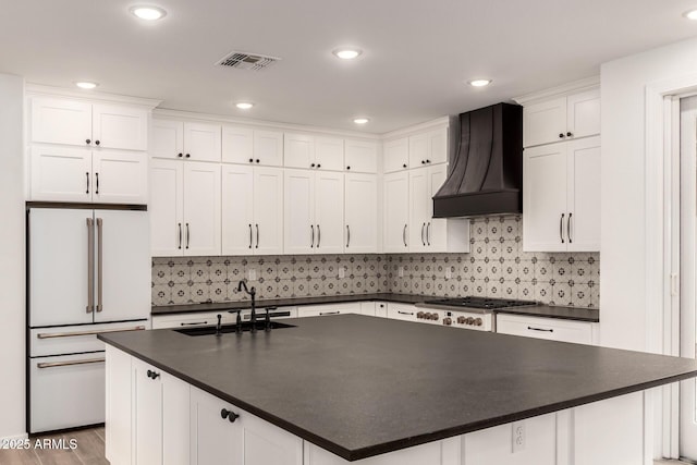 20412 W Thayer St, Buckeye, AZ 85396 - kitchen with high end white refrigerator, a sink, dark countertops, premium range hood, and white cabinetry