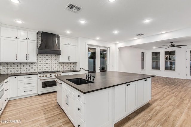 20412 W Thayer St, Buckeye, AZ 85396 - kitchen featuring high end white range oven, premium range hood, dark countertops, a sink, and light wood-style floors