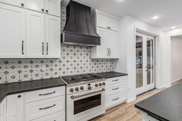 20412 W Thayer St, Buckeye, AZ 85396 - kitchen with high end range, custom range hood, light wood-style flooring, white cabinets, and tasteful backsplash