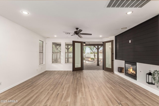 20412 W Thayer St, Buckeye, AZ 85396 - unfurnished living room with a large fireplace, light wood-style floors, a ceiling fan, baseboards, and recessed lighting