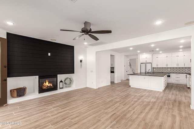 20412 W Thayer St, Buckeye, AZ 85396 - unfurnished living room featuring light wood-type flooring, a large fireplace, ceiling fan, baseboards, and recessed lighting