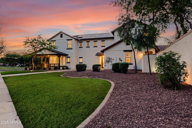 20412 W Thayer St, Buckeye, AZ 85396 - view of front of house featuring roof mounted solar panels, a front yard, covered porch, and stucco siding