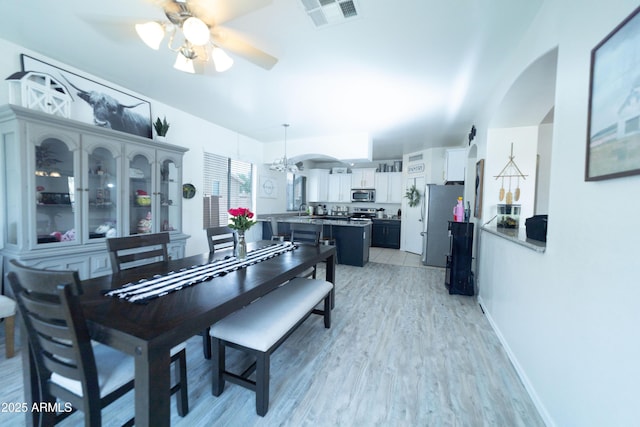 12161 W Flanagan St, Avondale, AZ 85323 - dining area featuring arched walkways, light wood-style flooring, a ceiling fan, and a chandelier