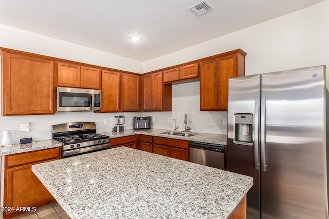 kitchen with light hardwood / wood-style floors, light stone countertops, stainless steel appliances, and sink