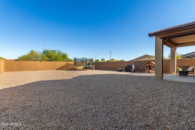 view of yard featuring a trampoline and a patio