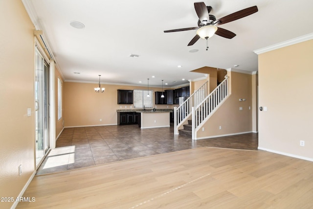 unfurnished living room featuring crown molding, ceiling fan with notable chandelier, and hardwood / wood-style flooring