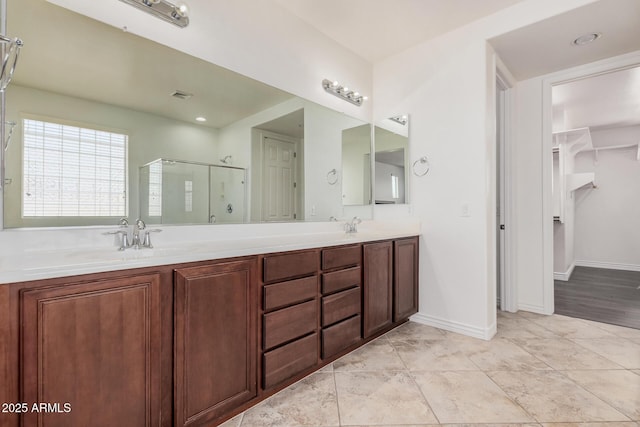 bathroom with double vanity, baseboards, visible vents, a shower stall, and a sink