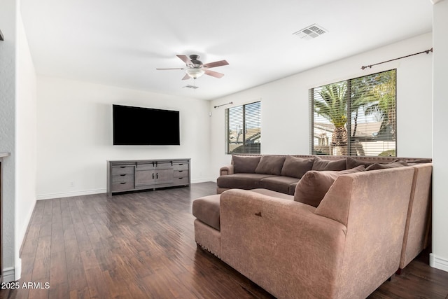 living room with dark wood-type flooring, visible vents, baseboards, and a ceiling fan