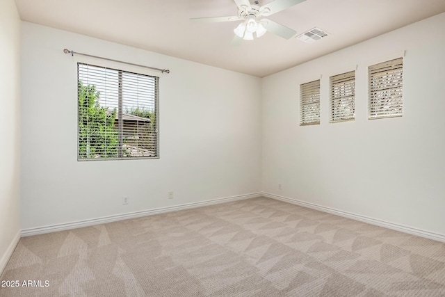 unfurnished room featuring baseboards, visible vents, a ceiling fan, and light colored carpet