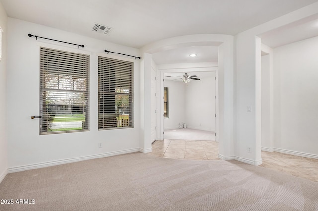 interior space with ceiling fan, arched walkways, visible vents, and baseboards