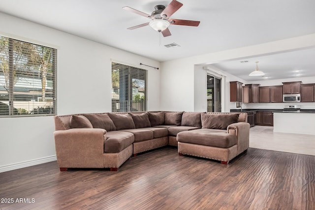 living area with dark wood-style floors, ceiling fan, visible vents, and baseboards