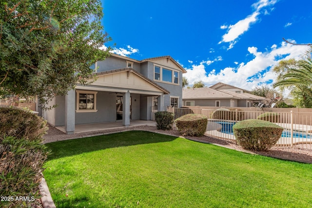 back of property with a fenced in pool, a patio, fence, a yard, and stucco siding