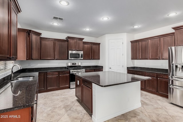 kitchen with appliances with stainless steel finishes, dark stone counters, visible vents, and a sink