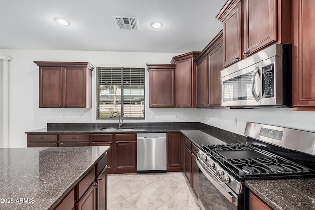 kitchen featuring dark stone counters, stainless steel appliances, and visible vents