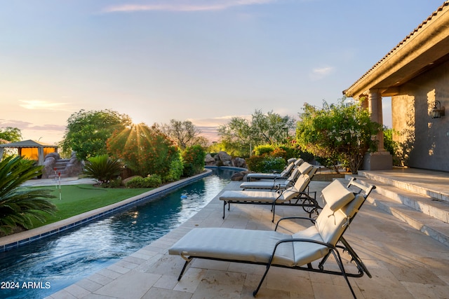 pool at dusk featuring a patio