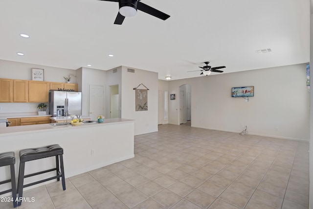 kitchen with ceiling fan, stainless steel fridge, light tile patterned flooring, and light brown cabinets