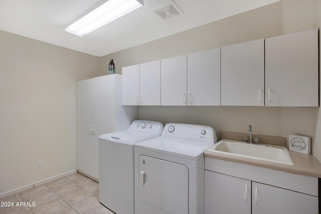 clothes washing area featuring light tile patterned flooring, cabinets, sink, and washing machine and clothes dryer