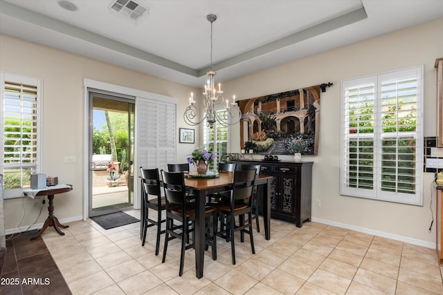 dining room featuring a chandelier, light tile patterned floors, a tray ceiling, and baseboards
