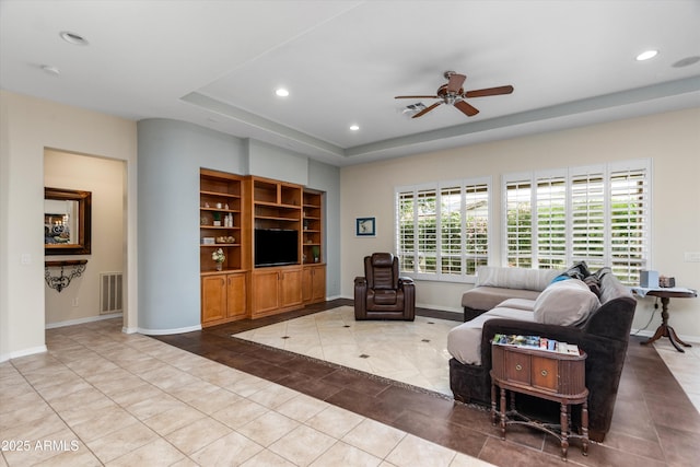 living room featuring light tile patterned floors, ceiling fan, recessed lighting, baseboards, and a raised ceiling