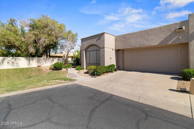 pueblo revival-style home featuring concrete driveway, stucco siding, and a garage