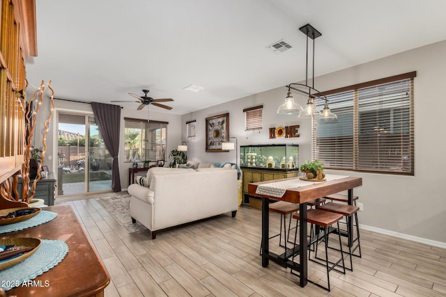 interior space featuring light wood-style floors, baseboards, a ceiling fan, and visible vents