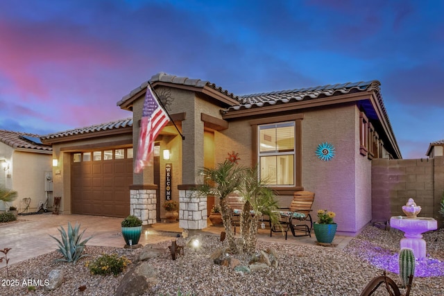 mediterranean / spanish home featuring fence, a tile roof, a garage, stucco siding, and concrete driveway