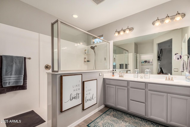 full bath featuring double vanity, visible vents, an enclosed shower, wood finished floors, and a sink