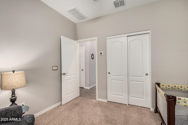 bedroom with a closet, baseboards, light colored carpet, and visible vents