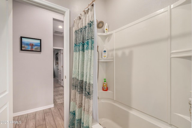bathroom with visible vents, baseboards, shower / bathtub combination with curtain, and wood finished floors