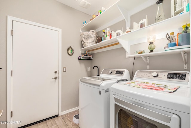 clothes washing area featuring baseboards, laundry area, washing machine and dryer, and light wood finished floors