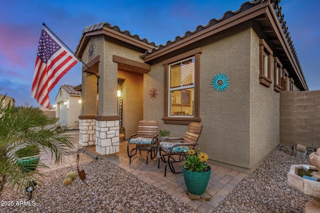 back of property with fence, stucco siding, a patio area, and a tiled roof