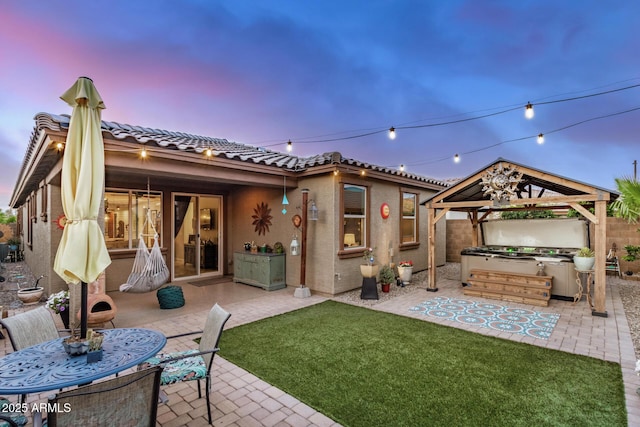 back of house featuring a gazebo, a tile roof, a jacuzzi, stucco siding, and a patio area
