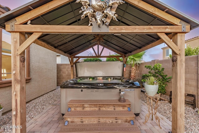 view of patio / terrace featuring a hot tub, a gazebo, and fence
