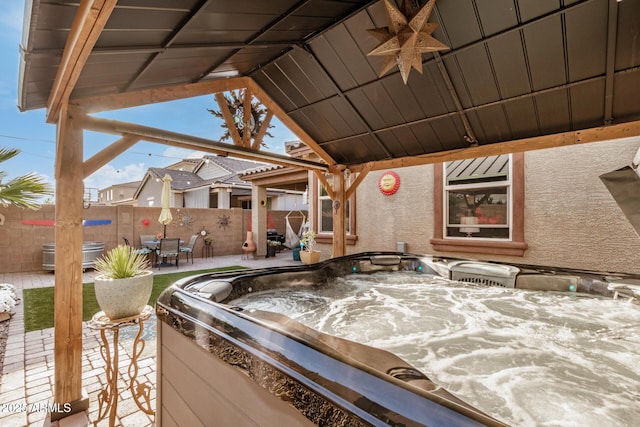 view of patio with a hot tub and fence